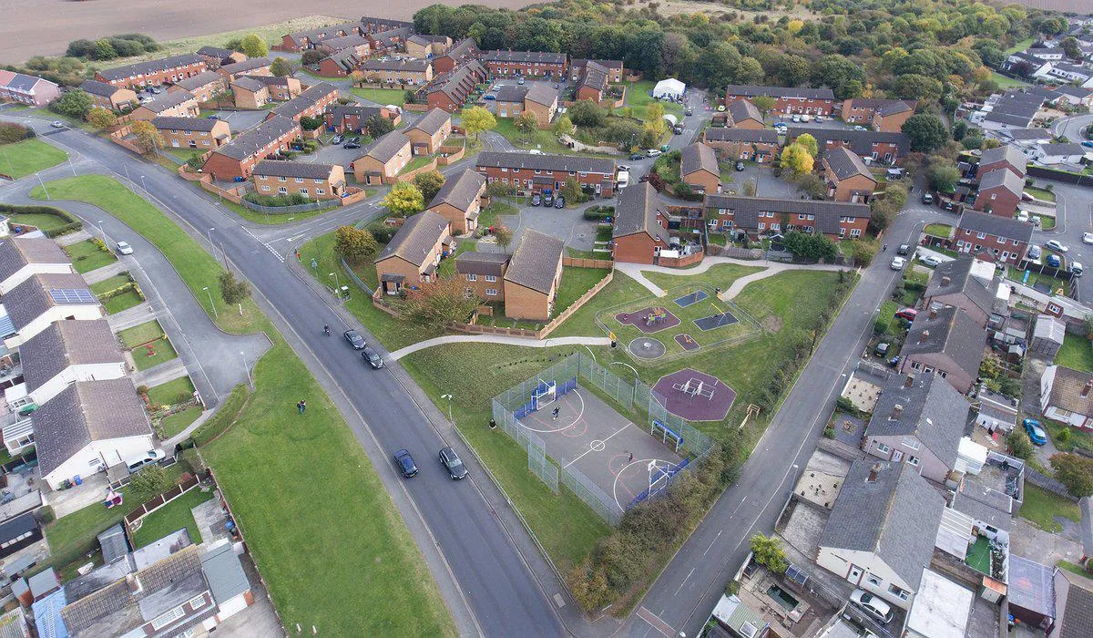 Llun o'r awyr o dai, man chwarae a choetir yn ystâd Parc Bruton yn y Rhyl