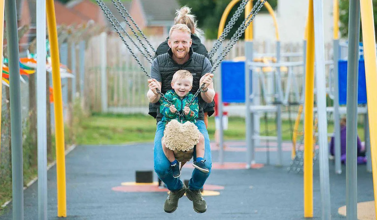 Teulu o 3 yn chwarae ar siglen rhaff newydd yn Rhuthun