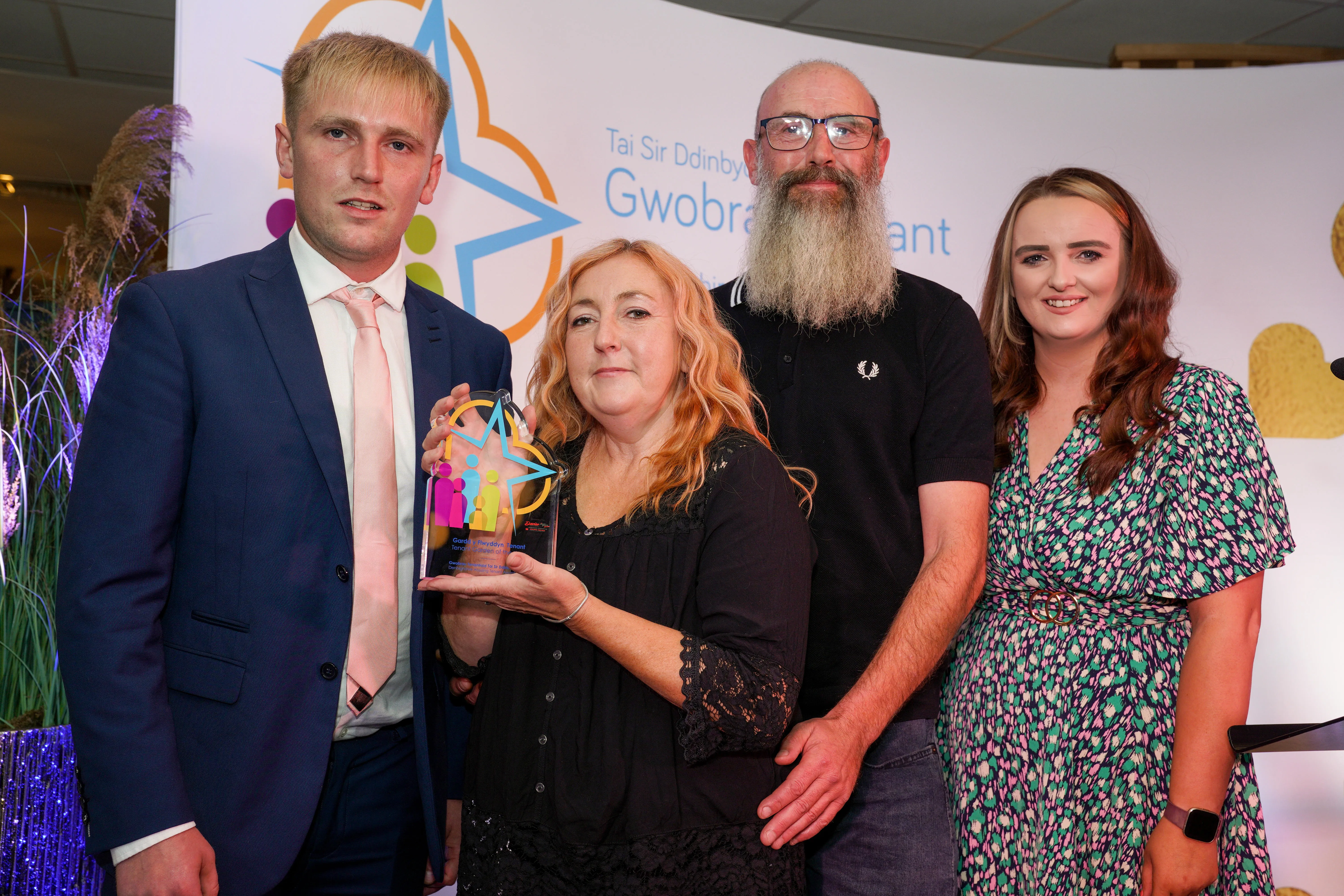 A group of people of various ages and genders stand together at an awards event.